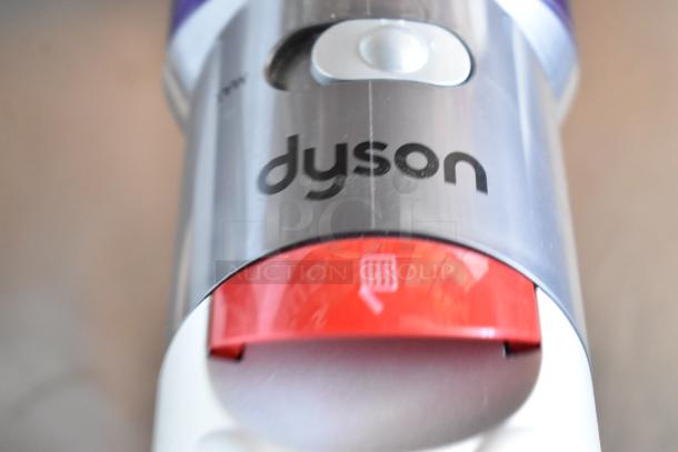 Close-up of Dyson vacuum cleaner showcasing brand logo and red filter indicator, highlighting sleek, modern design.