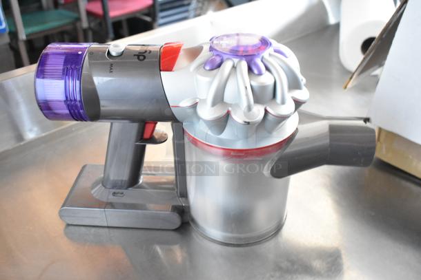 Handheld vacuum with purple accents, sleek design, transparent dustbin, and visible power settings. Appears in good condition.