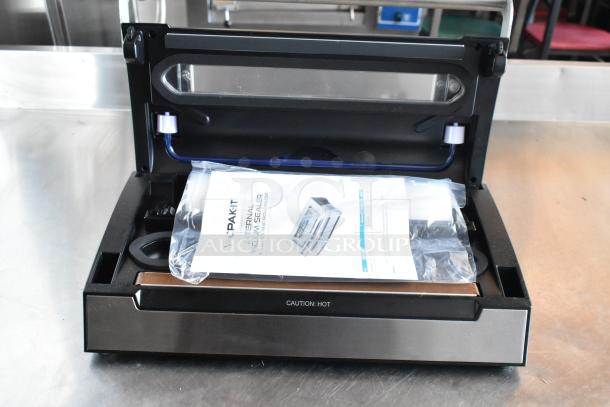 VacPak-It external vacuum sealer, black and stainless steel, open lid showing vacuum compartment, includes manual.