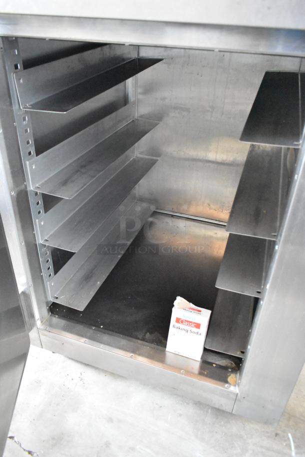 Commercial stainless steel oven with multiple shelves, used condition, includes a box of baking soda on the bottom shelf.