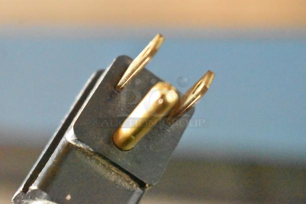 Close-up of a two-prong electrical plug with a grounding pin, showing minor wear on the metal blades.
