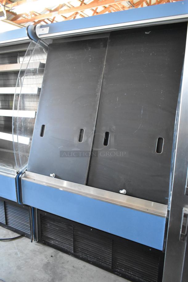Large commercial refrigerator with sliding doors, blue exterior, visible shelving, fair condition, lot tag marked "65."