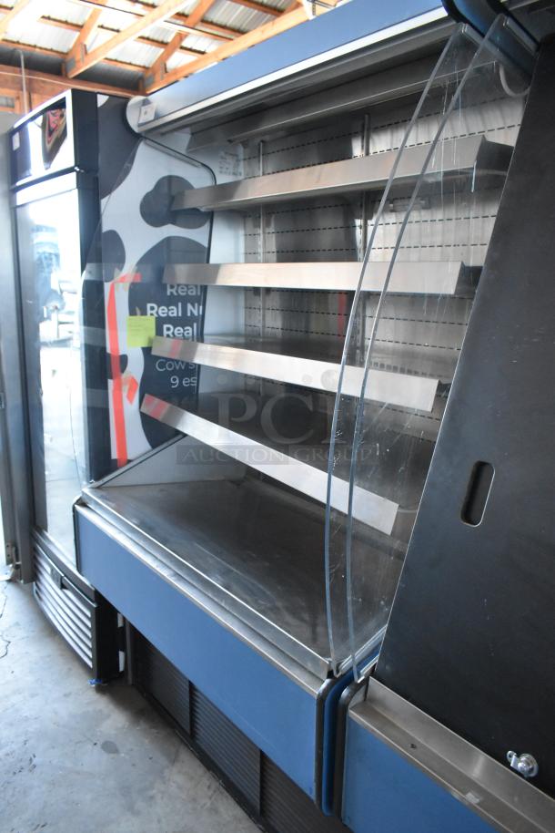 Commercial refrigerated display case, blue exterior, three metal shelves, clear front panel, in used condition.
