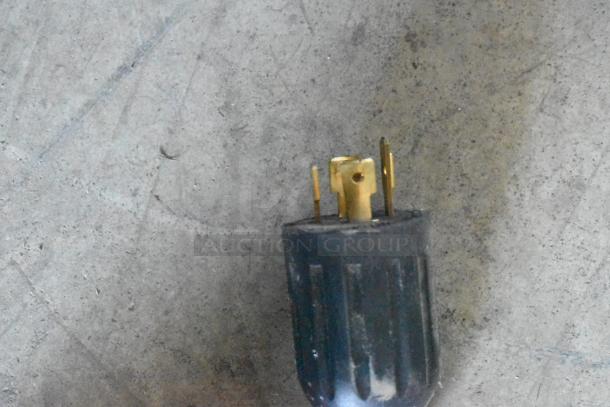 Black electrical plug with three brass prongs, slightly worn condition, suitable for heavy-duty use.