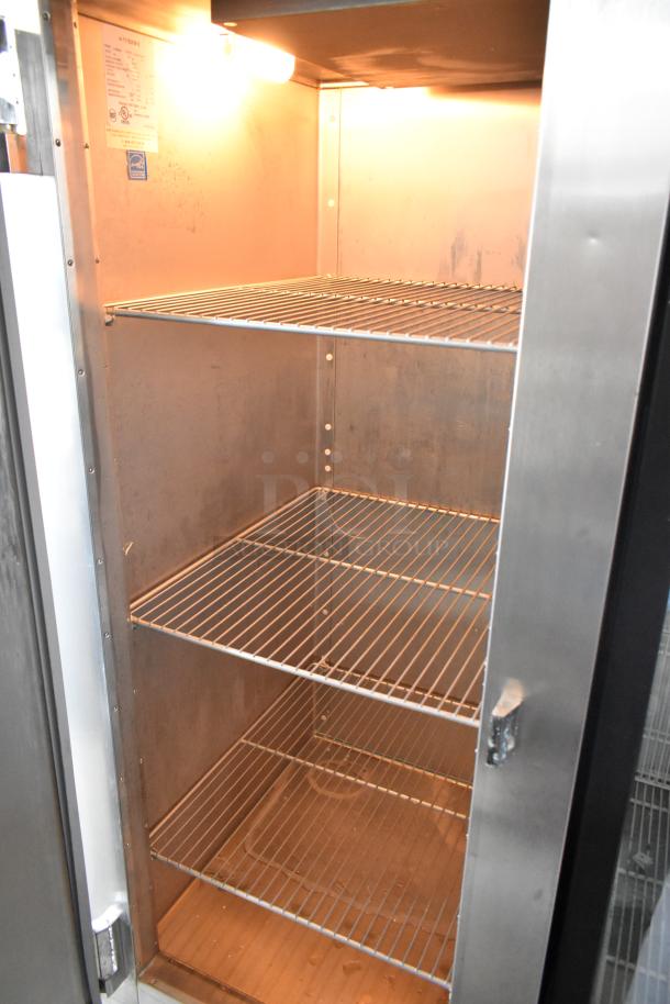 Commercial stainless steel refrigerator with three wire shelves, interior light, and visible label indicating model details.