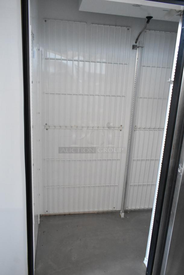 White metal storage cage with vertical bars, concrete floor, and wiring visible. Suitable for secure storage. Appears in good condition.