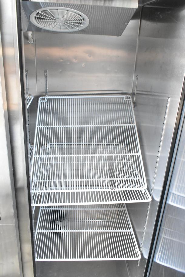 Commercial stainless steel refrigerator interior with adjustable wire shelves. Clean condition, suitable for restaurant use.