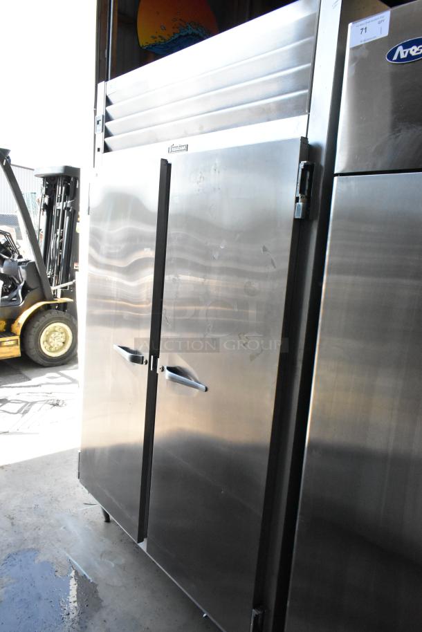 Stainless steel commercial refrigerator, double doors, True brand, moderate wear, visible label and item number tag.