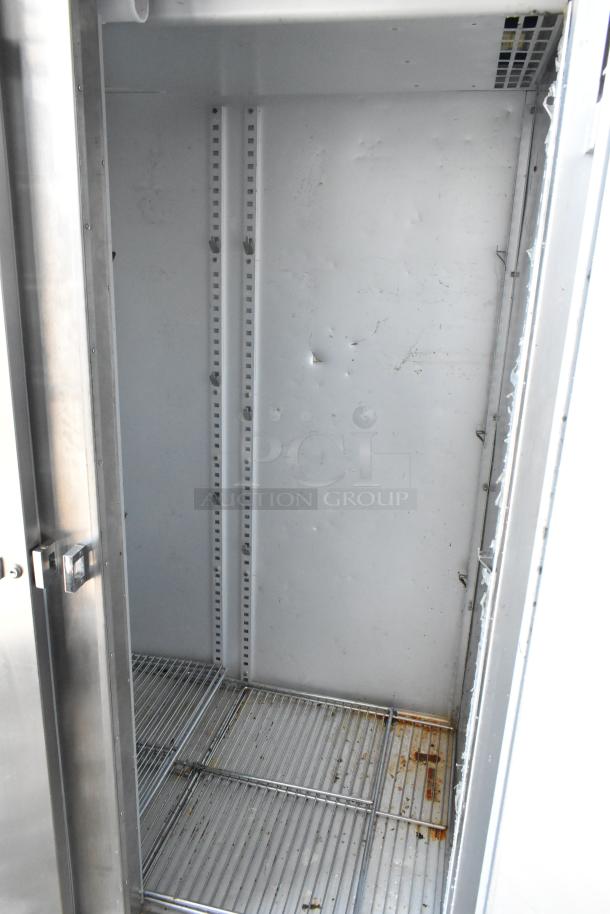 Commercial stainless steel refrigerator interior, visible shelving. Used condition with scuffs and rust on bottom shelf.