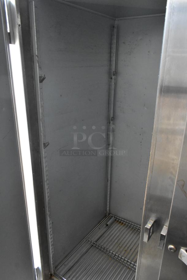 Commercial stainless-steel warming cabinet, interior view, showing metal shelving. Features adjustable shelves. Moderate wear.
