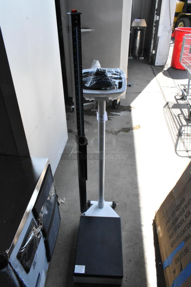 Medical height and weight scale, black and white, with height rod. Condition appears good, includes plastic-wrapped accessories.