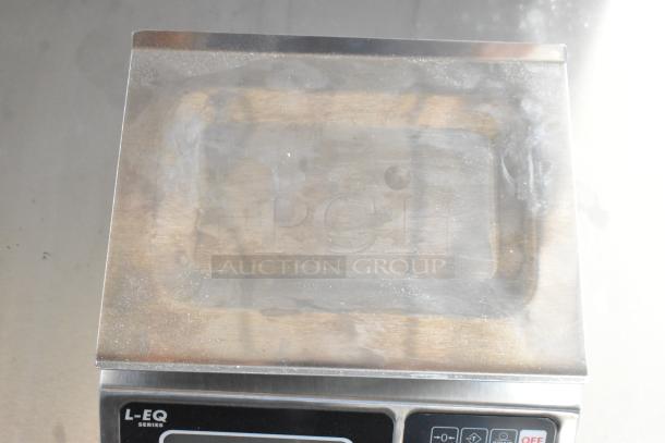 Stainless steel commercial scale, L-EQ series, used condition with visible wear, digital display and control panel below.