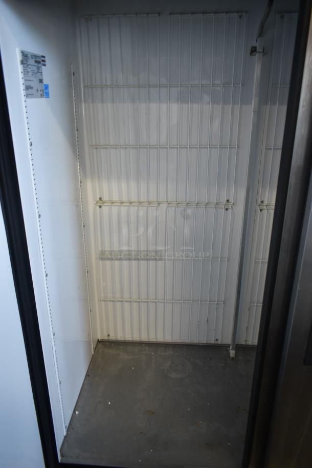 Commercial refrigerator interior with wire shelving, clean condition. Tag indicates model and specifications.