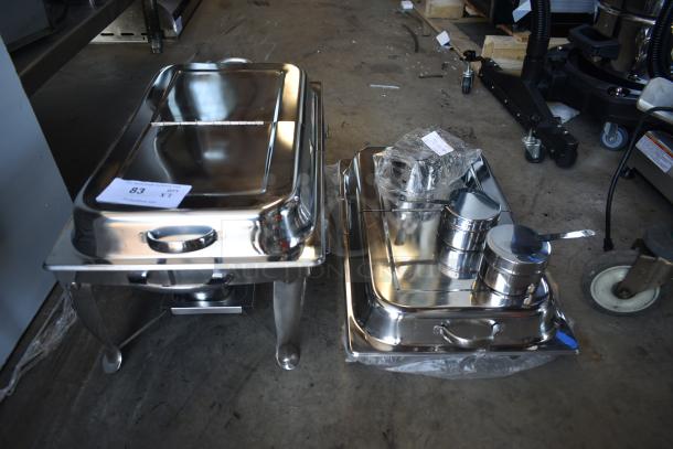 Two stainless steel chafing dishes with lids, one with serving utensils and wrapped accessories. Label marked as item 83.