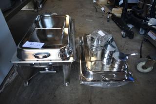 Two stainless steel chafing dishes with lids, one with serving utensils and wrapped accessories. Label marked as item 83.