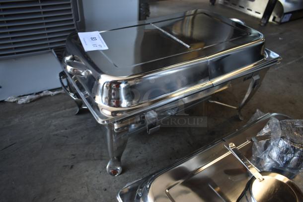 Stainless steel chafing dish with lid, sturdy legs, and handles, marked with auction number 83, in good condition.