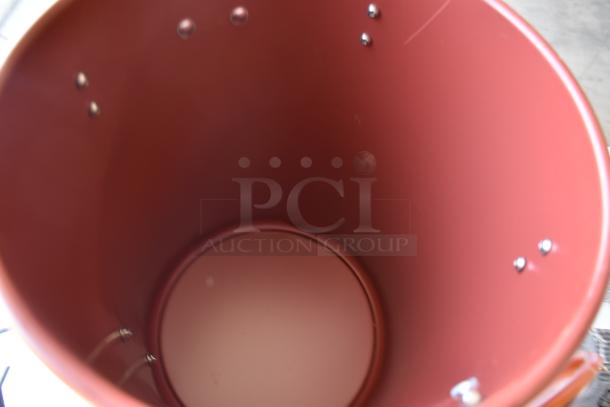 Red metal bucket with riveted construction, smooth interior, and slight visible wear, suitable for various uses.
