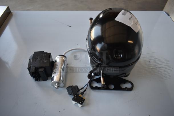 Compressor unit with accessories, black finish, includes electrical components and metal cylinder. Label with barcode visible.