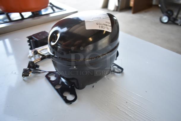 Black refrigeration compressor with attached mountings and wires, label reads "HTE12BK3 R-134a," in good condition.