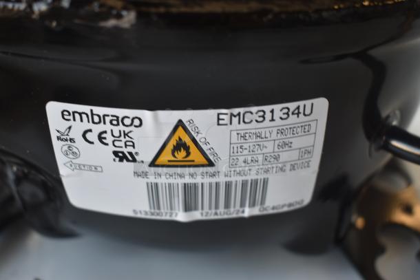 Embraco EMC3134U compressor, thermally protected, 115-127V, 60Hz. Warning label: "Risk of Fire." Made in China.