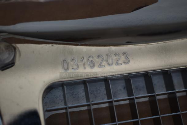 Close-up of a metal object with engraved number "03162023," showing a grid structure. Condition appears slightly worn.