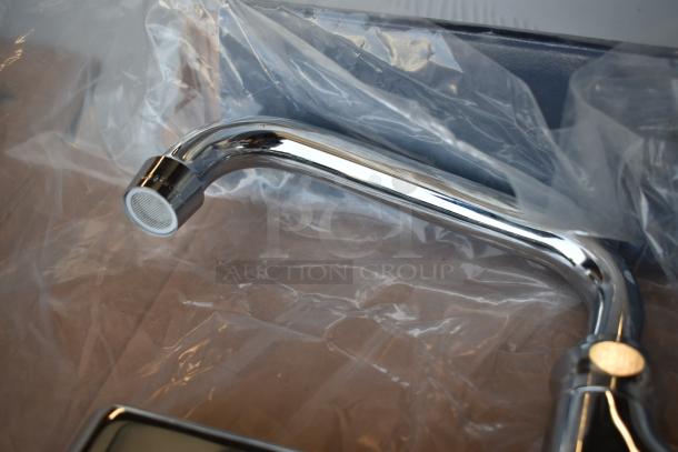 Chrome kitchen faucet in pristine condition, wrapped in protective plastic, displaying a sleek design and reflective finish.