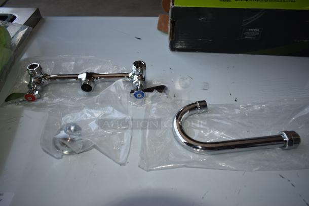 Chrome kitchen faucet set, new in packaging. Features dual handles with red and blue indicators. Includes spout and connectors.