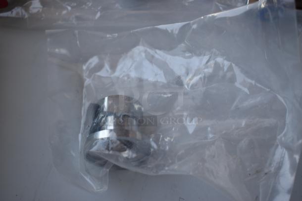 Metal component in plastic packaging, appears new. Silver finish, cylindrical shape. No visible labels or markings.