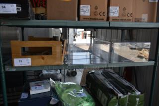 Wooden crate with item label "93 QTY VP1", clear acrylic bin, and cardboard boxes labeled "Oracle" on metal shelving in warehouse.