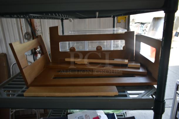 Wooden shelving components on a metal rack, light brown finish, various panel sizes, suitable for assembly or repair.