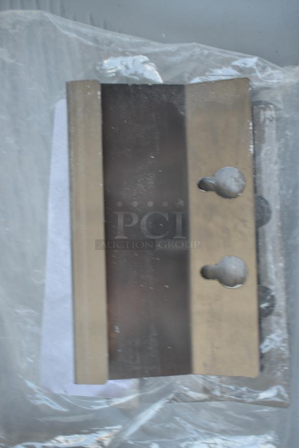 Metal cutting blade with two mounting holes, packaged in protective plastic. Appears unused, no visible labels or markings.