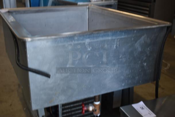 Industrial stainless steel sink, large basin, visible piping, and electrical cords. Slight wear, auction tag attached.
