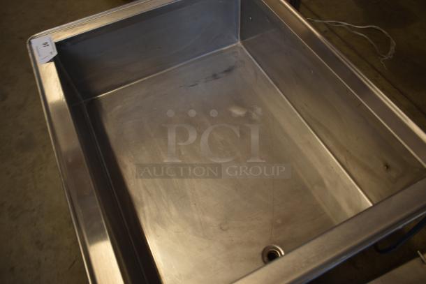 Stainless steel industrial sink with drainage hole, light surface wear, ID tag in corner. Ideal for commercial use.