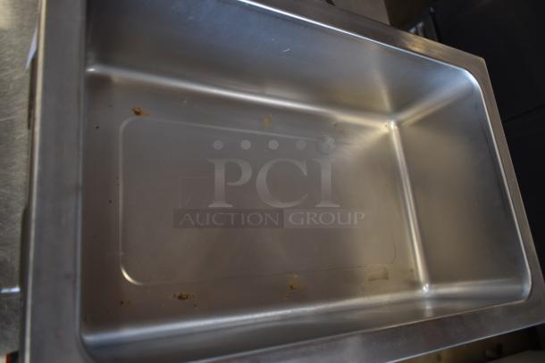 Stainless steel pan, rectangular shape, slight scratches, residue present, no visible brand markings, suitable for kitchen use.