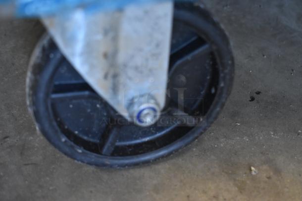 Close-up of a black plastic caster wheel with a metal bracket. The wheel shows signs of wear. No visible markings.