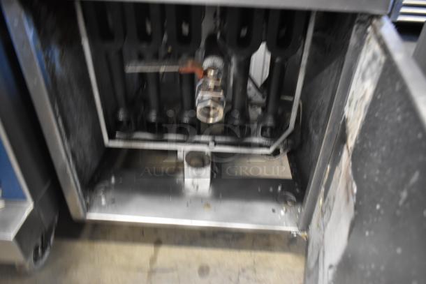 Industrial machine component with metal pipes and valve. Signs of wear on metal surfaces. No visible labels or markings.