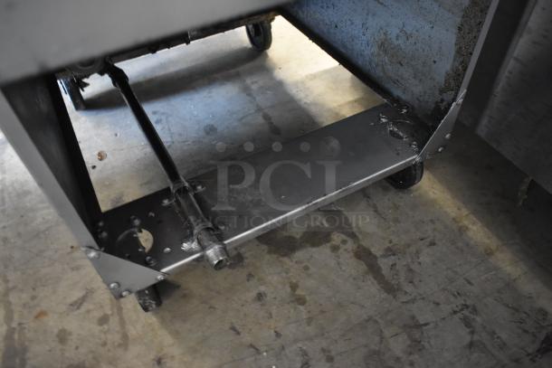 Industrial metal frame with wheels and pipe fittings, likely part of machinery, showing signs of wear.