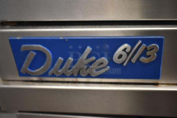 Metal appliance with "Duke 6/13" blue label, indicating model or serial number. Slight wear visible on label edges.