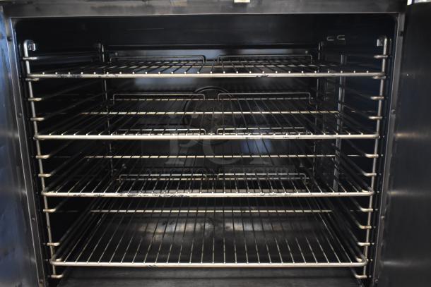 Commercial stainless steel oven interior with five metal racks, clean condition, ideal for large-scale baking needs.