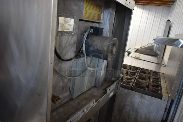 Commercial stainless steel kitchen appliance with attached motor, showing signs of use. Labels indicate safety instructions and model details.
