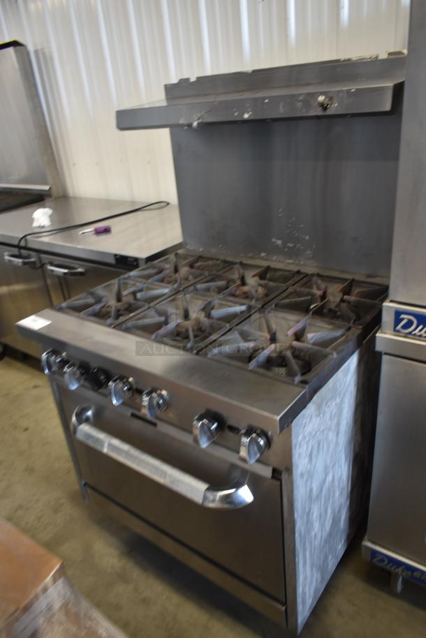 Commercial gas range with six burners, stainless steel, used condition. Features control knobs and storage below.
