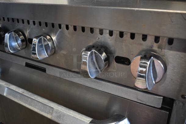 Stainless steel commercial oven with four control knobs, showing minimal wear, ideal for professional kitchens.