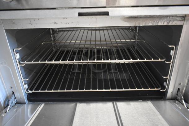 Commercial stainless steel oven interior with two wire racks, clean condition, visible wear on edges, suitable for heavy-duty use.