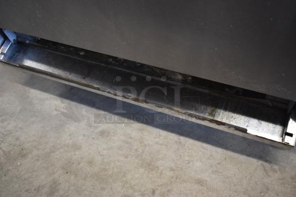 Metal commercial refrigerator base, showing wear and rust. No visible tags or markings. Suitable for repair or parts.