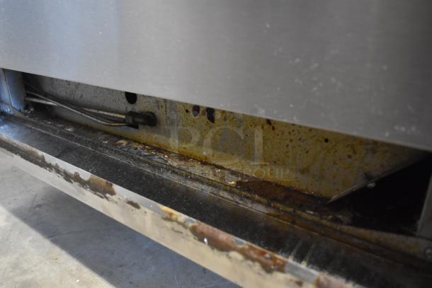 Commercial appliance underside showing visible rust and wear, with exposed cables and metal surfaces needing maintenance.