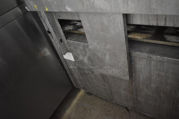 Industrial stainless steel oven, showing signs of wear and rust. Durable construction, no visible branding, on casters.