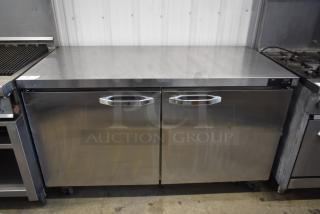 Stainless steel two-door undercounter refrigerator with durable handles, showing slight surface wear. Brand label: "Atosa."