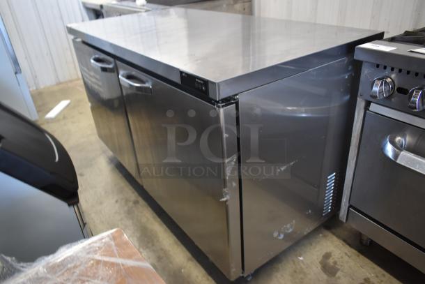 Commercial stainless steel under-counter refrigerator with two doors and digital controls, showing signs of wear.