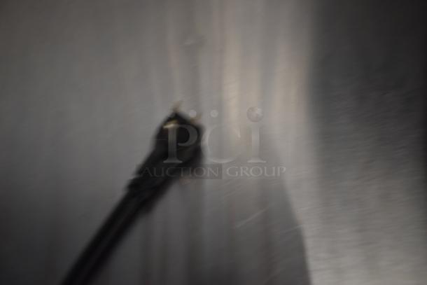 Blurry image of an electrical plug against a reflective surface. Details are indistinct.
