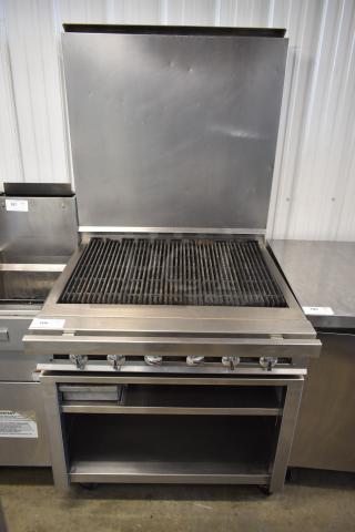 Commercial stainless steel grill with five control knobs, shelving below, and a protective splash guard. Good condition, tag 106.